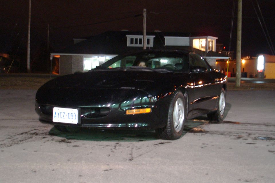 Black coupe with a white license plate reading AYCZ-093 parked at night