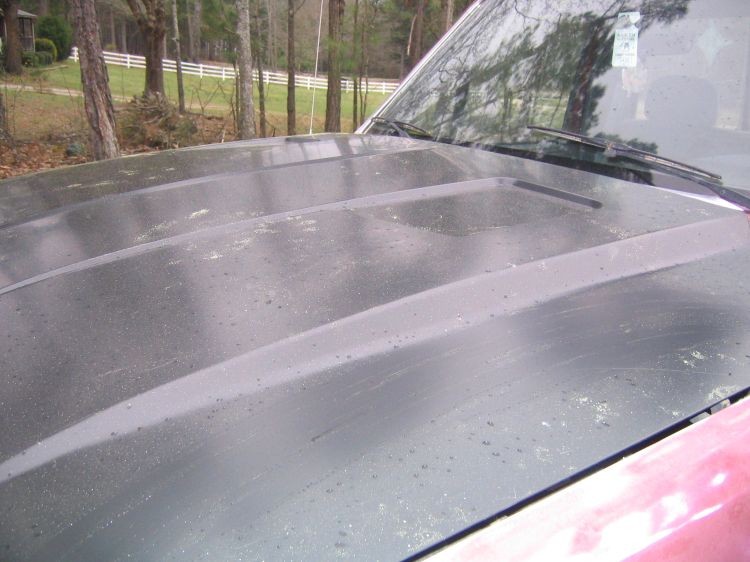 Gray primer cowl hood on red pickup, close view toward windshield and wipers