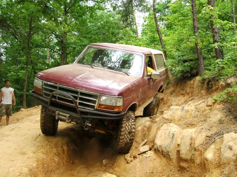 1993 Ford Bronco - This 1993 Ford Bronco tackles a challenging off-road course, its tires gripping the uneven terrain.