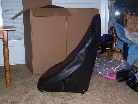 1988 Suzuki Samurai - A black car seat cover, possibly for a Suzuki Samurai, is shown in front of large cardboard boxes.