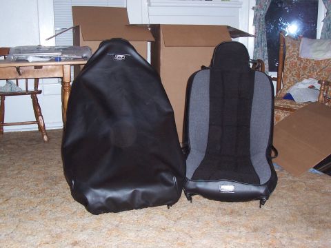 1988 Suzuki Samurai - Two car seats are shown, one covered in black vinyl and the other a fabric racing seat, with cardboard boxes in the background.
