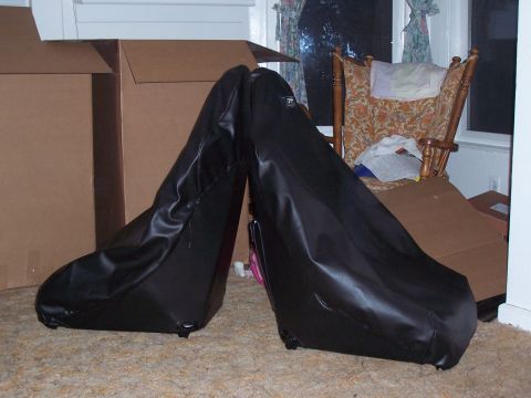 1988 Suzuki Samurai - Two black car seats are covered in protective plastic and leaning indoors.
