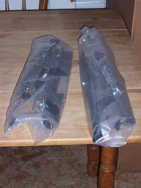1988 Suzuki Samurai - Two automotive parts are shown individually wrapped in clear plastic on a wooden surface.