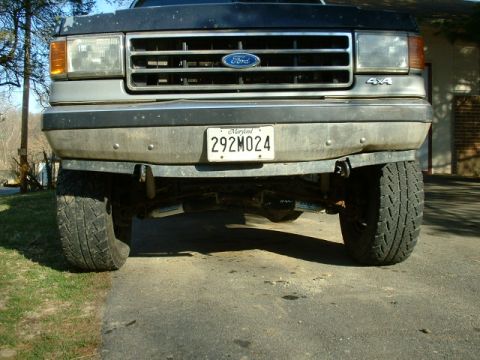 1991 Ford Bronco - The front grille and headlights of a Ford truck are visible, along with its license plate and tires.