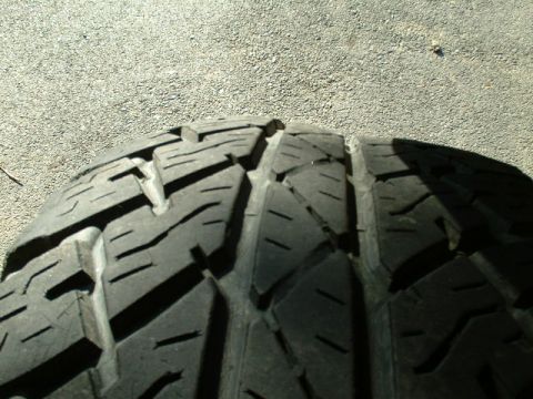 1991 Ford Bronco - Close-up of a tire tread on a gravel surface, showing the pattern and wear marks.
