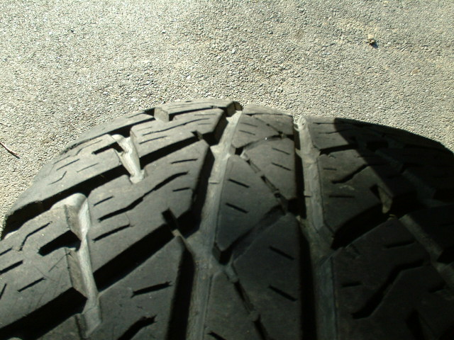 Close-up of all-terrain tire tread showing wear on the outer tread blocks