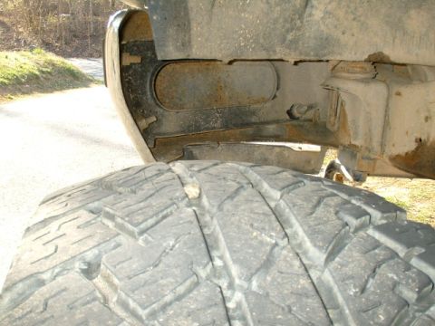 1991 Ford Bronco - The underside of a vehicle, focusing on the tire and frame structure, reveals signs of age and use.