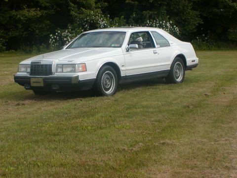 1990 Lincoln Mark VII - This 1990 Lincoln Mark VII coupe is shown from a three-quarter front angle, parked outdoors on a grassy area.