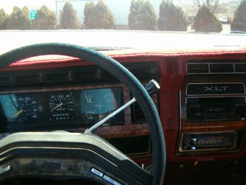 1985 Ford Bronco - Interior view of a vintage Ford truck's dashboard, woodgrain accents and an XLT trim designation.