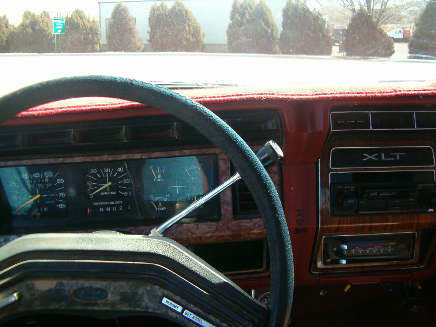 Dashboard of a vintage Ford truck with woodgrain trim, showing an XLT badge and an aftermarket JVC stereo