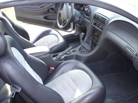 1998 Ford Taurus - The interior of a car, likely a Ford Mustang, shows its seats, dashboard, and manual gear shifter.