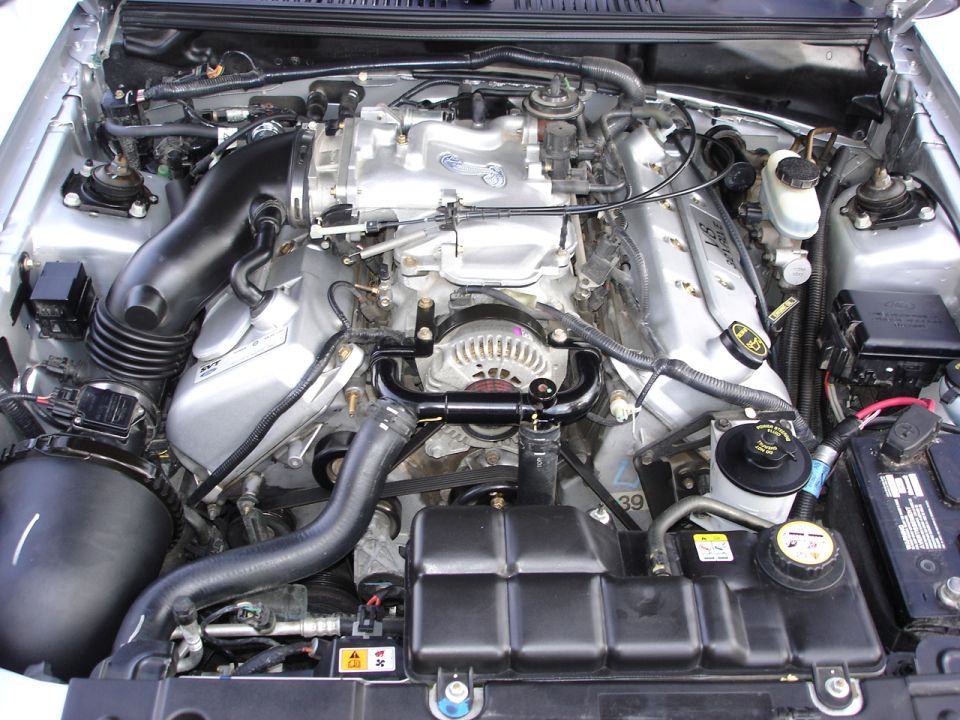 Ford Mustang engine bay with V8 engine, air intake, alternator, and battery visible