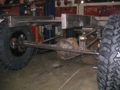 1978 Ford Bronco - A custom off-road chassis is shown with large tires and visible suspension components in a workshop setting.