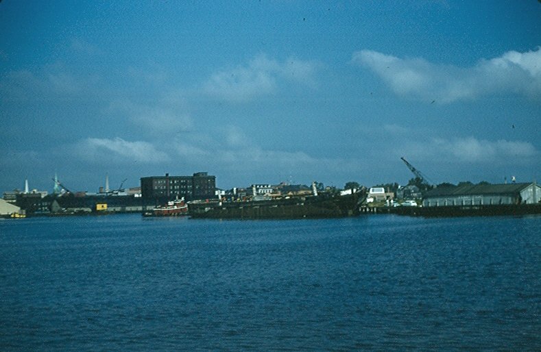 Waterfront industrial scene with ships and buildings under a blue sky