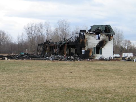 1994 Ford Bronco - A house is heavily damaged by fire, with two vehicles visible in the background.