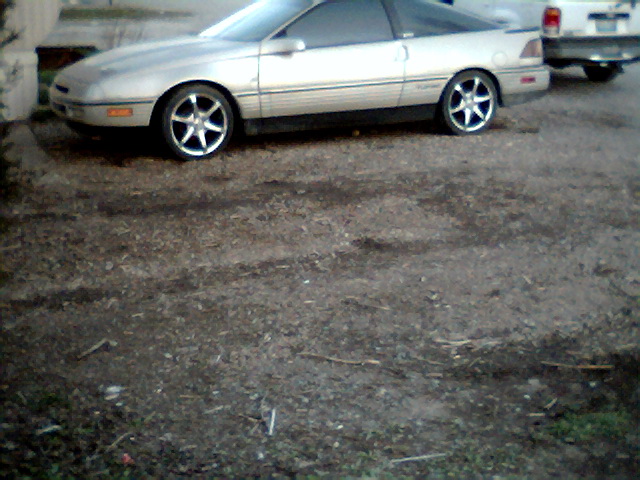 Silver 1989 Ford Probe coupe parked on gravel, another vehicle partially visible behind it