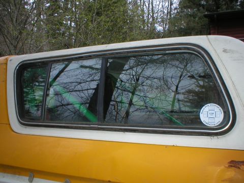 1978 Ford Bronco - A sticker is visible on the side window of a yellow and white pickup truck with a camper shell.