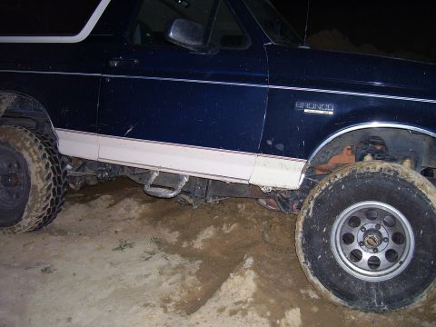 1992 Ford Bronco - This 1992 Ford Bronco is seen stuck in a muddy area, with its side profile visible.
