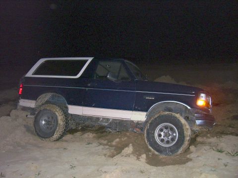1992 Ford Bronco - Ford Bronco stuck in sand at night, showing its lifted suspension and off-road tires.