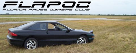 1994 Ford Probe - A black 1994 Ford Probe sits parked on a grassy field under an overcast sky.