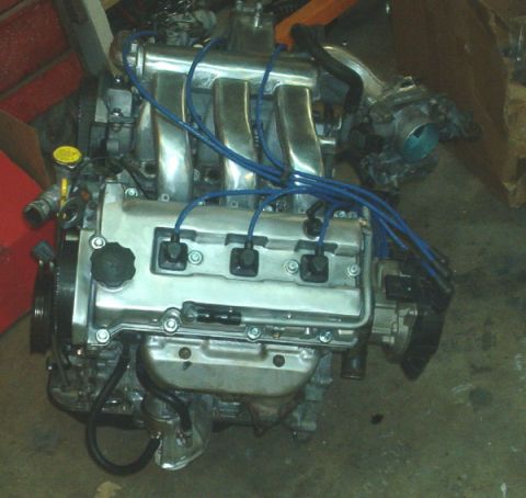 1994 Mazda MX-3 - A V6 engine is shown, likely a replacement part, with its intake manifold and spark plug wires visible.