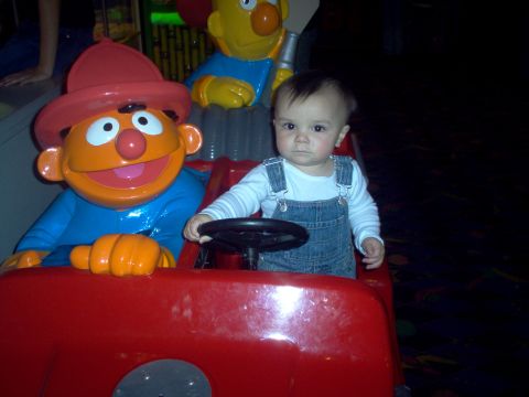 2004 Ford F-150 - A baby sits in a red toy car, holding the steering wheel, with Sesame Street characters Ernie and Bert beside them.