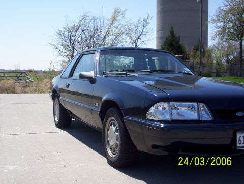 1991 Ford Mustang - A dark blue 1991 Ford Mustang coupe is parked outdoors, showing its 5.0 badge and front quarter view.