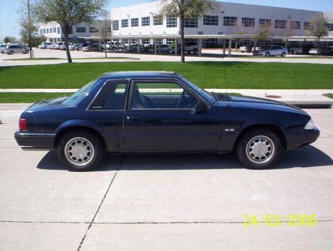 1991 Ford Mustang - Side profile of a dark blue 1991 Ford Mustang coupe with a "5.0" badge.