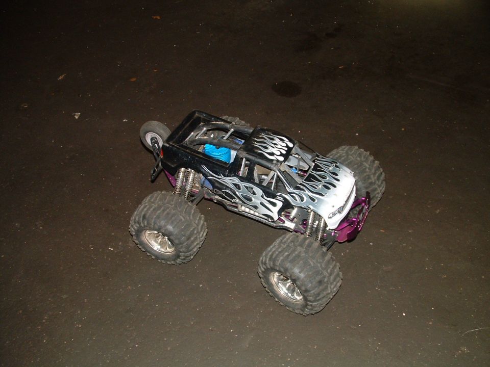 Remote control monster truck with flame decals and oversized tires on a dark surface