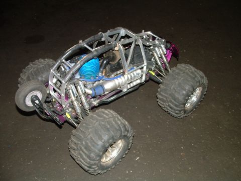 1994 Ford Bronco - A remote control monster truck with large tires and an exposed engine sits on a dark surface.