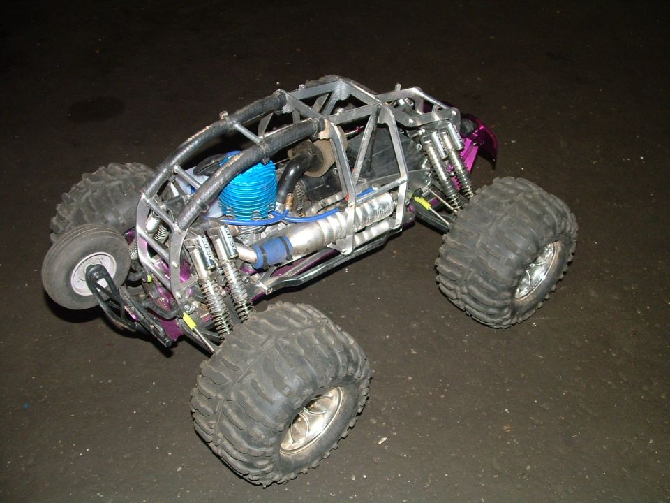 Remote control monster truck with a silver roll cage, purple body panels, and a blue engine