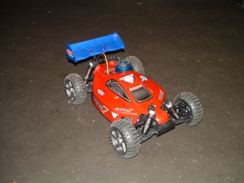1994 Ford Bronco - A red remote control buggy with a prominent blue spoiler is shown from a three-quarter front view.