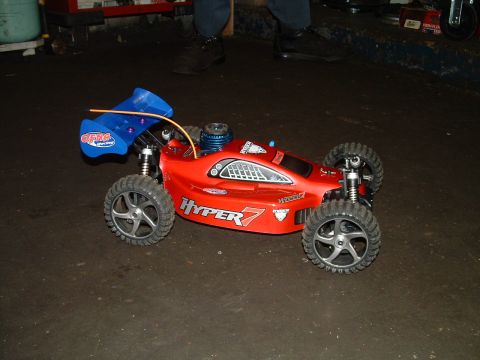 1994 Ford Bronco - A red remote control buggy with a blue spoiler is shown from a 3/4 front view.