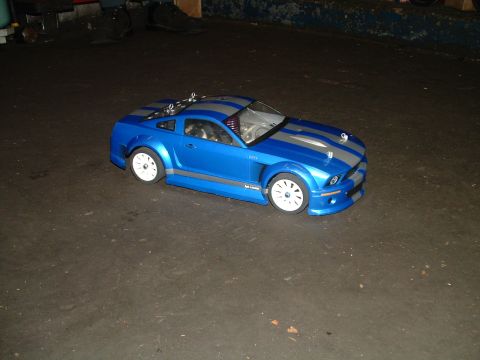 1994 Ford Bronco - This blue remote control car features silver racing stripes and white rims, seen on a dark, textured surface.