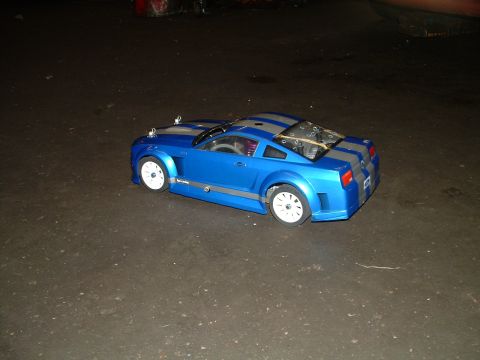 1994 Ford Bronco - A blue remote control car with gray stripes sits on a dark, textured surface.