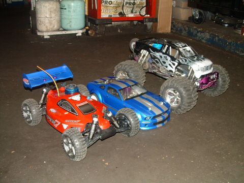 1994 Ford Bronco - A collection of three remote-controlled vehicles, including a red buggy, a blue muscle car, and a monster truck, are displayed on a garage…