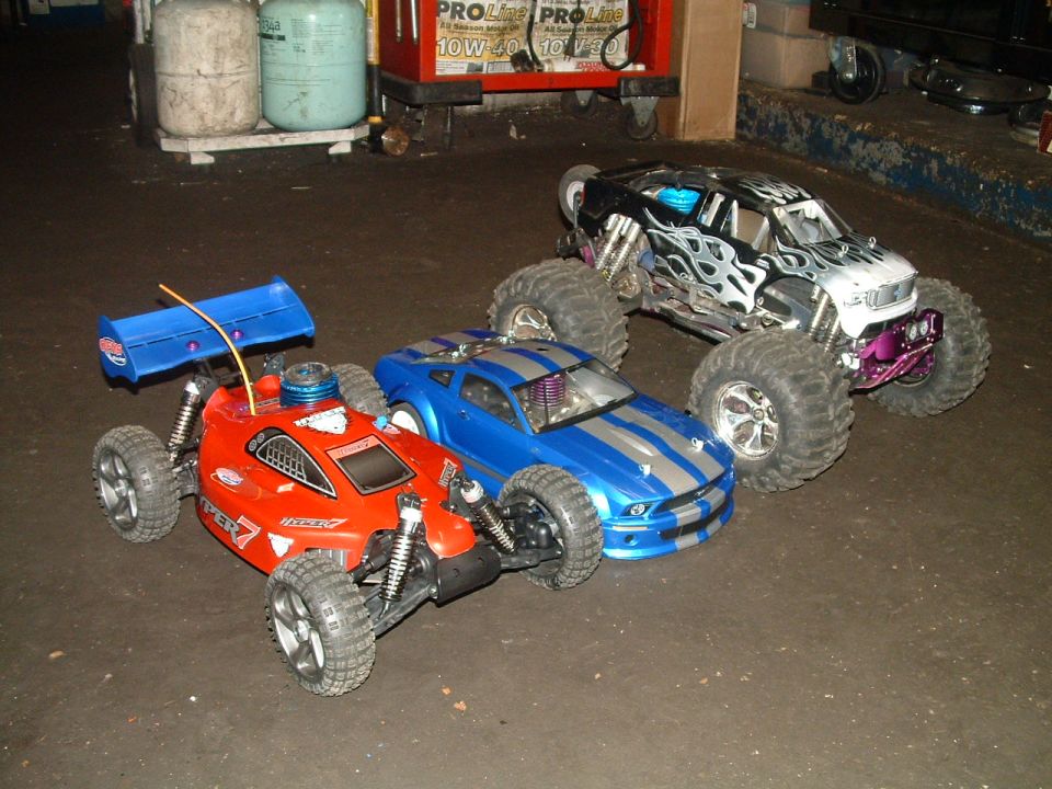 Three RC cars: red buggy, blue muscle car, and monster truck with flame decals