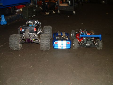 1994 Ford Bronco - Three RC vehicles are parked side-by-side on a concrete floor, with tools and equipment in the background.