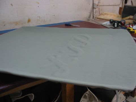 1985 Ford Crown Victoria LTD - A light gray headliner with embossed text is laid out on a table, possibly for installation or repair.