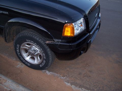 2003 Ford Ranger - Front corner of a black 2003 Ford Ranger truck with visible damage to the front bumper.