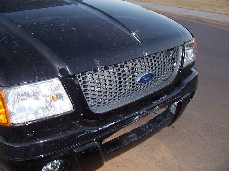 Black Ford Ranger front end with honeycomb grille and damaged bumper