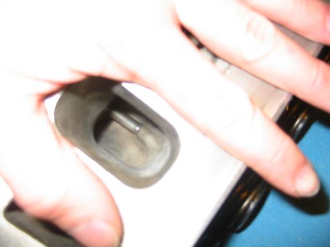 1985 Ford Crown Victoria LTD - A hand holds a metal engine component, obscuring most of the view and making identification difficult.