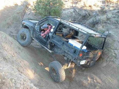 1986 Ford Bronco - Custom flatbed truck navigating a steep dirt incline off-road.