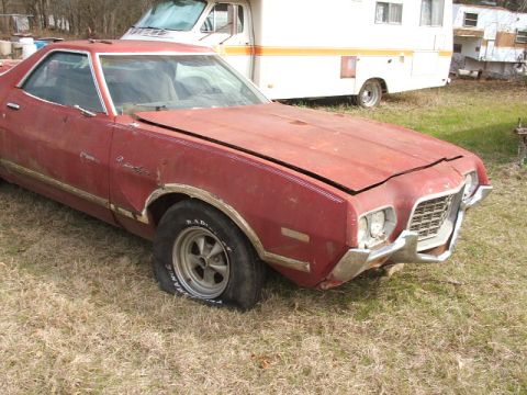 1972 Ford Ranchero - This 1972 Ford Ranchero shows significant wear and tear, including a flat tire and damage to its front bumper and grille.