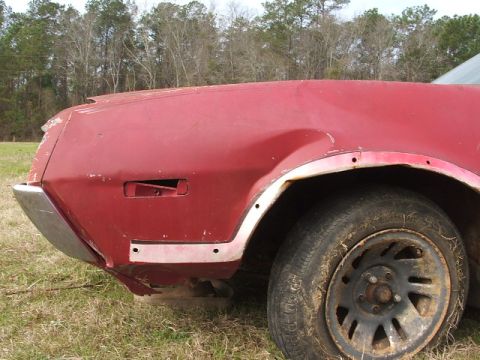 1972 Ford Ranchero - A damaged red car fender is visible from the side, with a dirty tire and wheel.
