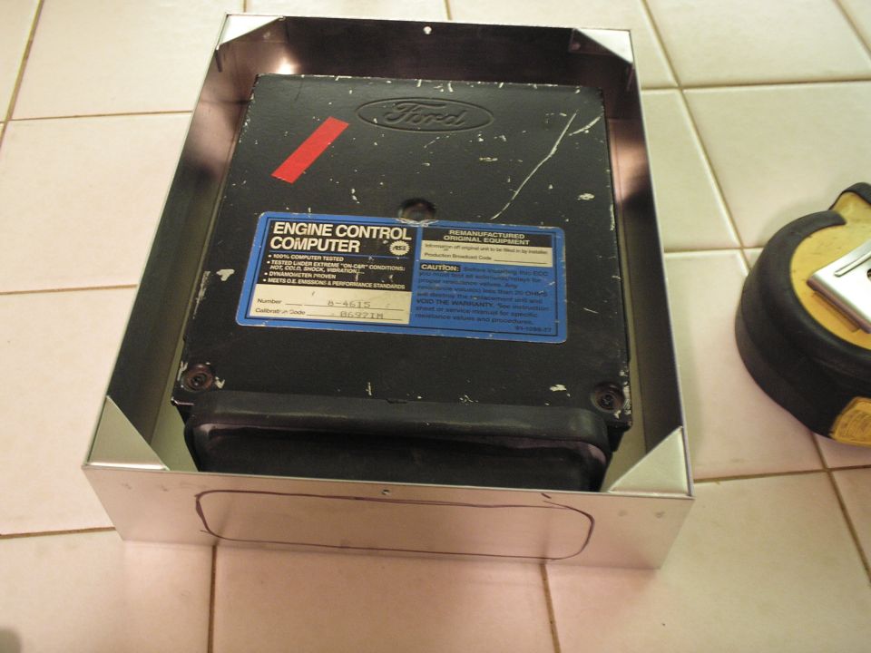 Ford engine control computer with blue reman label sitting in polished sheetmetal mount box