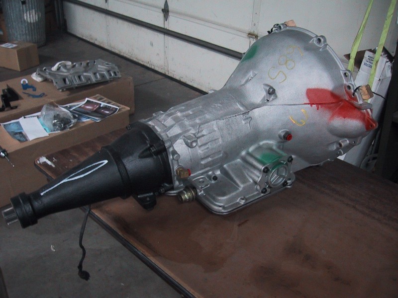 Rebuilt automatic transmission with black tailshaft sitting on table in garage