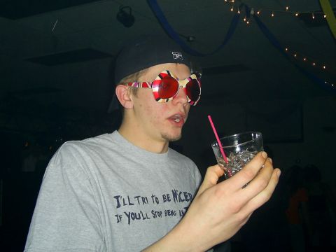 1985 Ford Bronco - Man wearing novelty glasses and drinking from a glass with a straw. Text on shirt is partially visible.