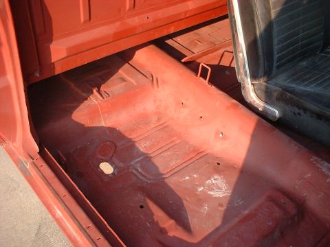 1967 Ford Ranchero - The interior floor of a vehicle is visible, showing the seat and door frame with red paint.