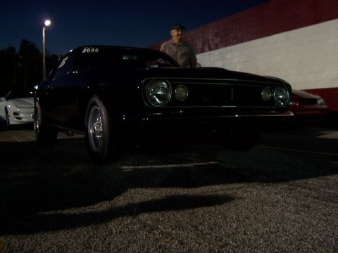 1994 Ford Probe - A black muscle car is parked at night, with a man standing behind it and another car to the side.